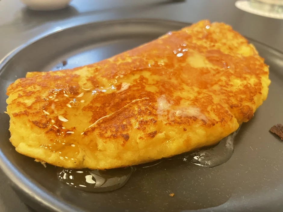こんがりと焼けたフレンチトーストが黒い皿に盛り付けられており、上にはつやつやとしたシロップがたっぷりとかかっている