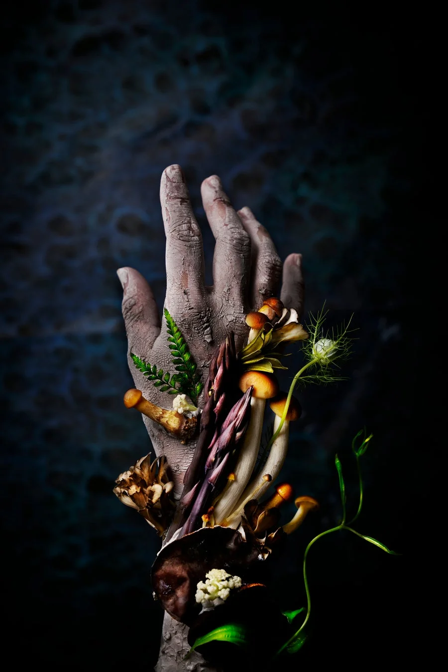 土に覆われた手からキノコや植物が芽吹いているアート作品