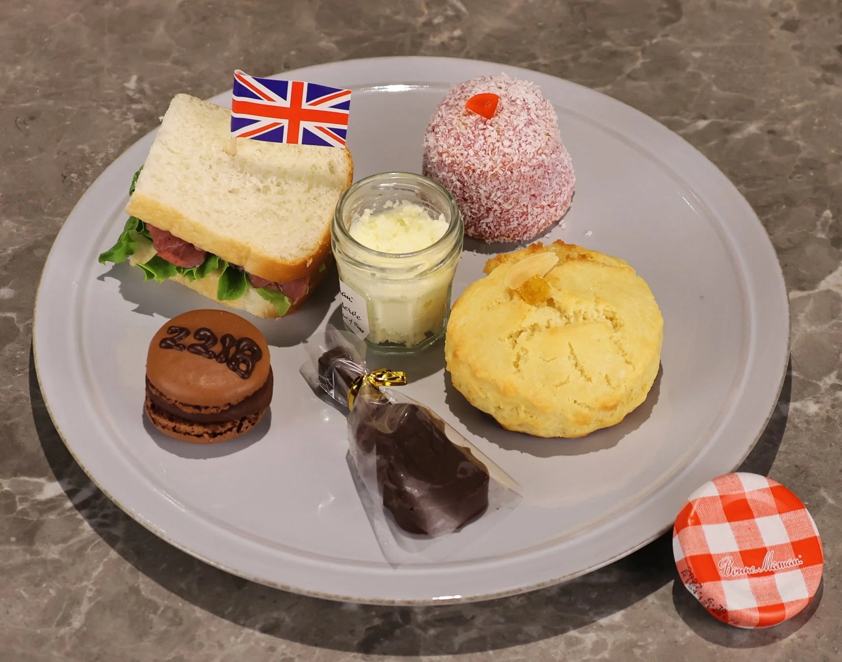 英国旗が飾られたサンドイッチ、スコーン、マカロンなど、様々なデザートが並べられたアフタヌーンティーセット