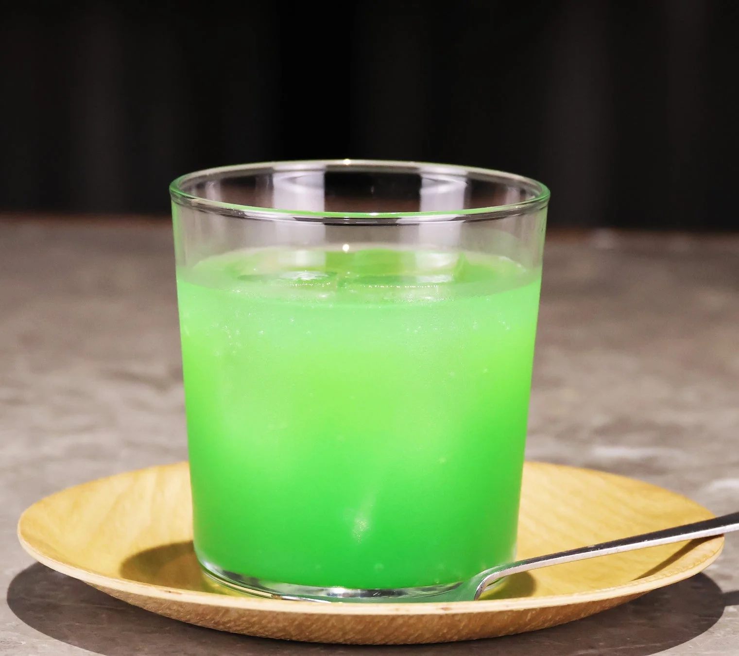 透明なグラスに入った鮮やかな緑色の飲み物