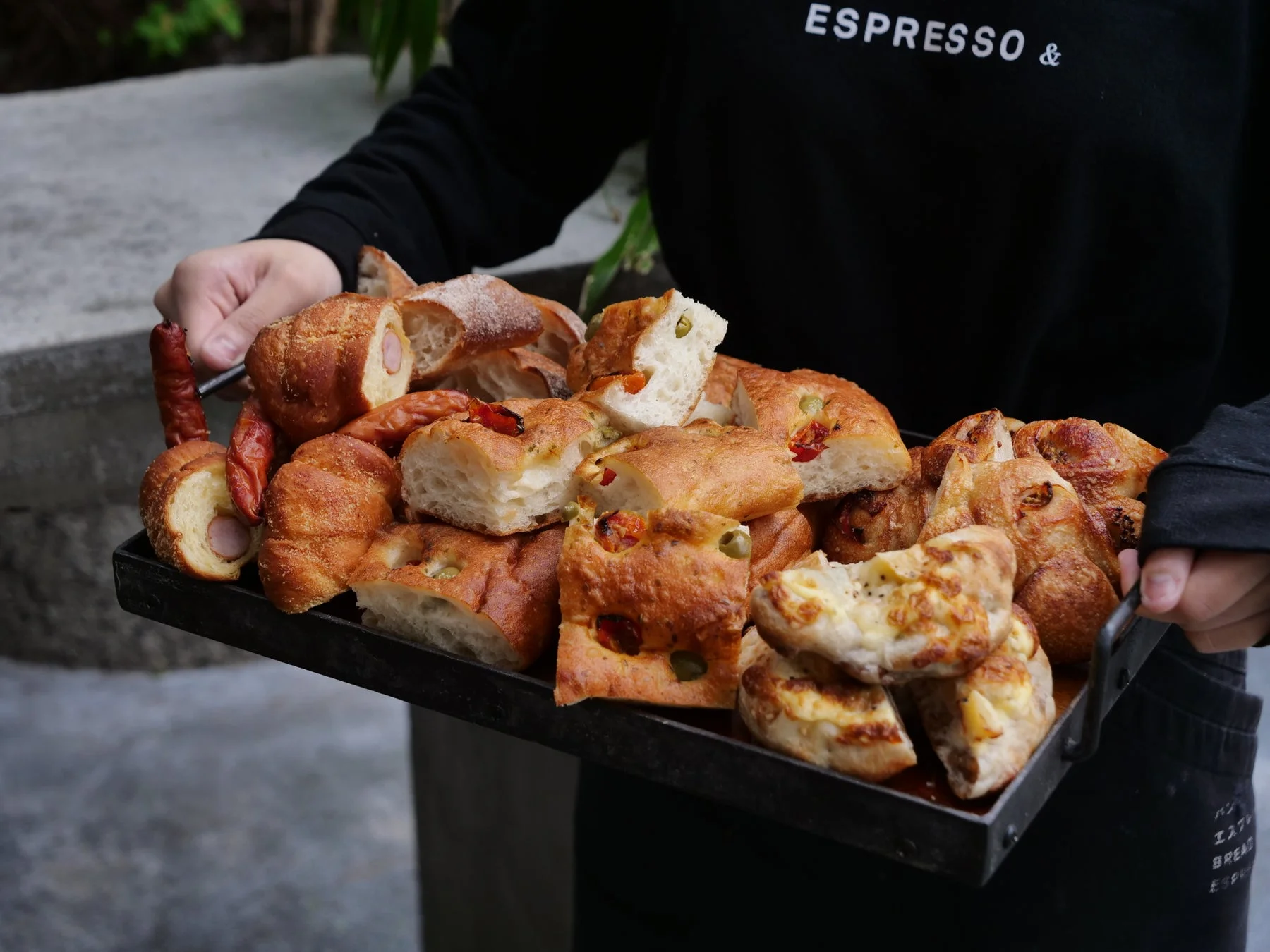 黒いトレーに焼きたての様々な種類のパンが山盛りにされています