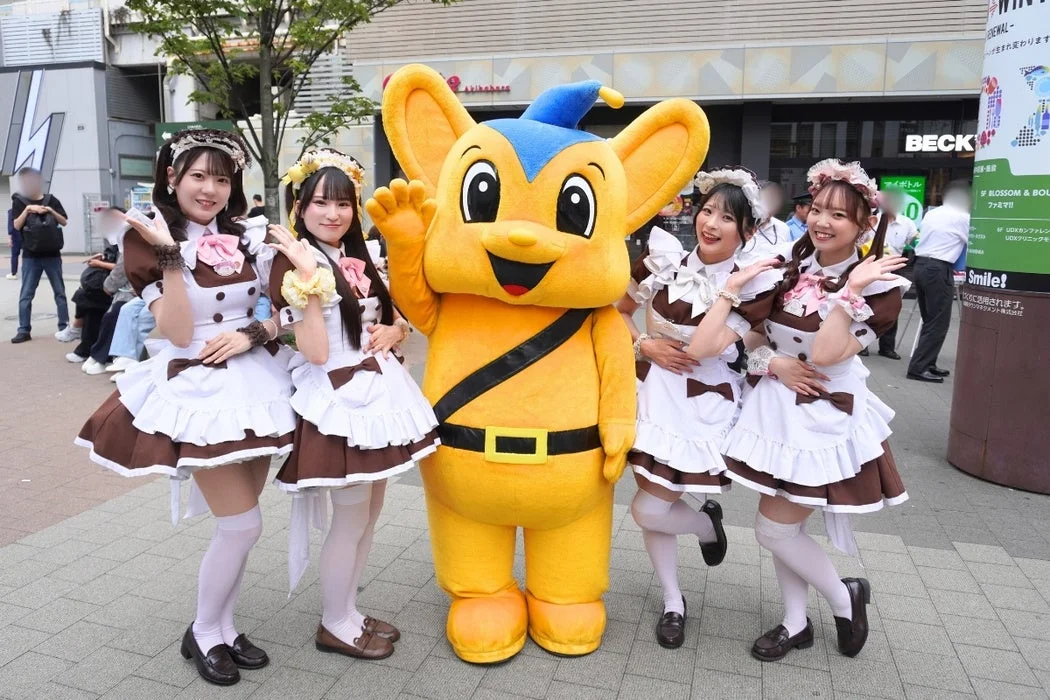 メイドとマスコットキャラクターが街頭で笑顔