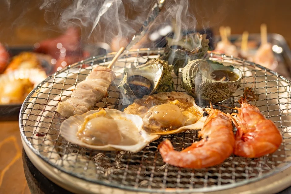 炭火で焼かれるホタテ、エビ、サザエ、串焼きなどの新鮮な海鮮料理