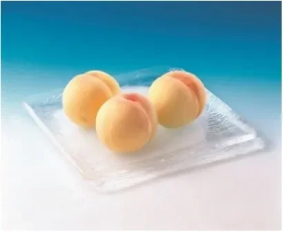 透明なガラスの皿に、皮をむいた状態の瑞々しい桃が3つ並べられています
