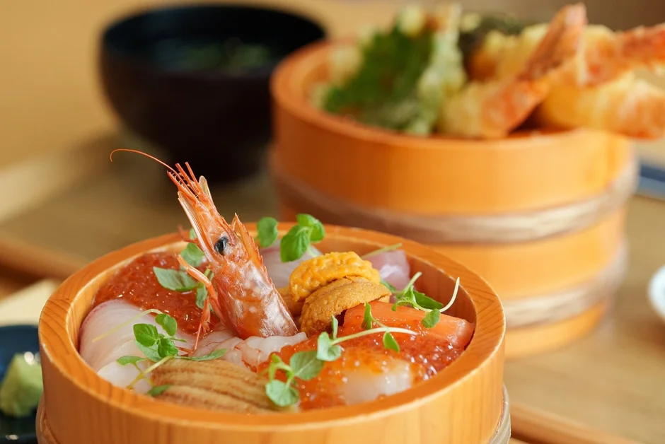 新鮮な海鮮が豪華に盛り付けられた海鮮丼と、揚げたての天ぷらが並ぶ和食の定食