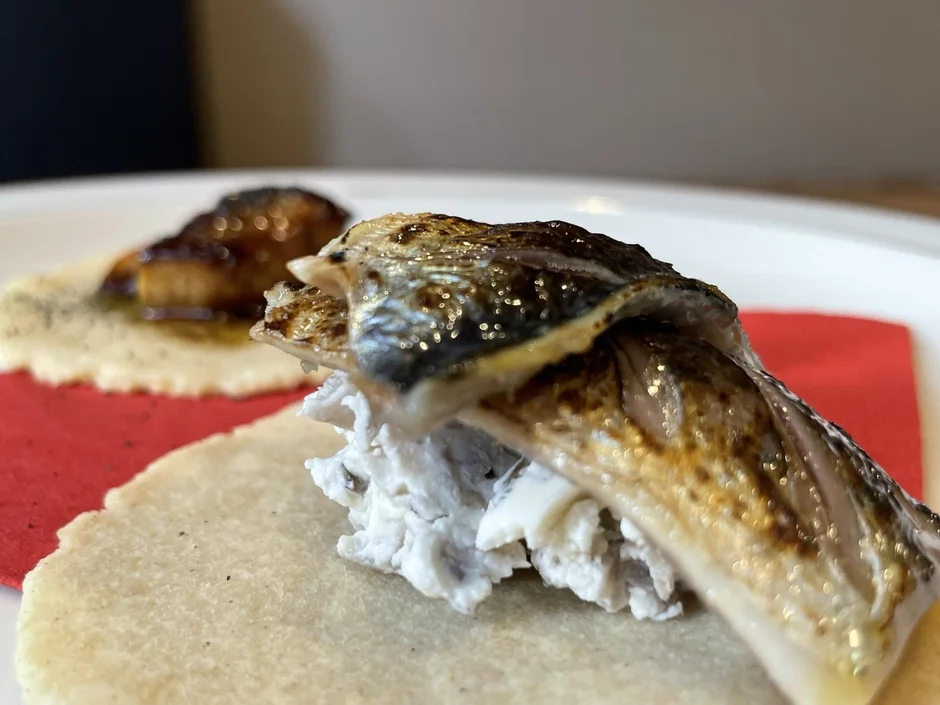 香ばしく焼き上げられた魚が、白いクリームとフラットブレッドの上に美しく盛り付けられた一品