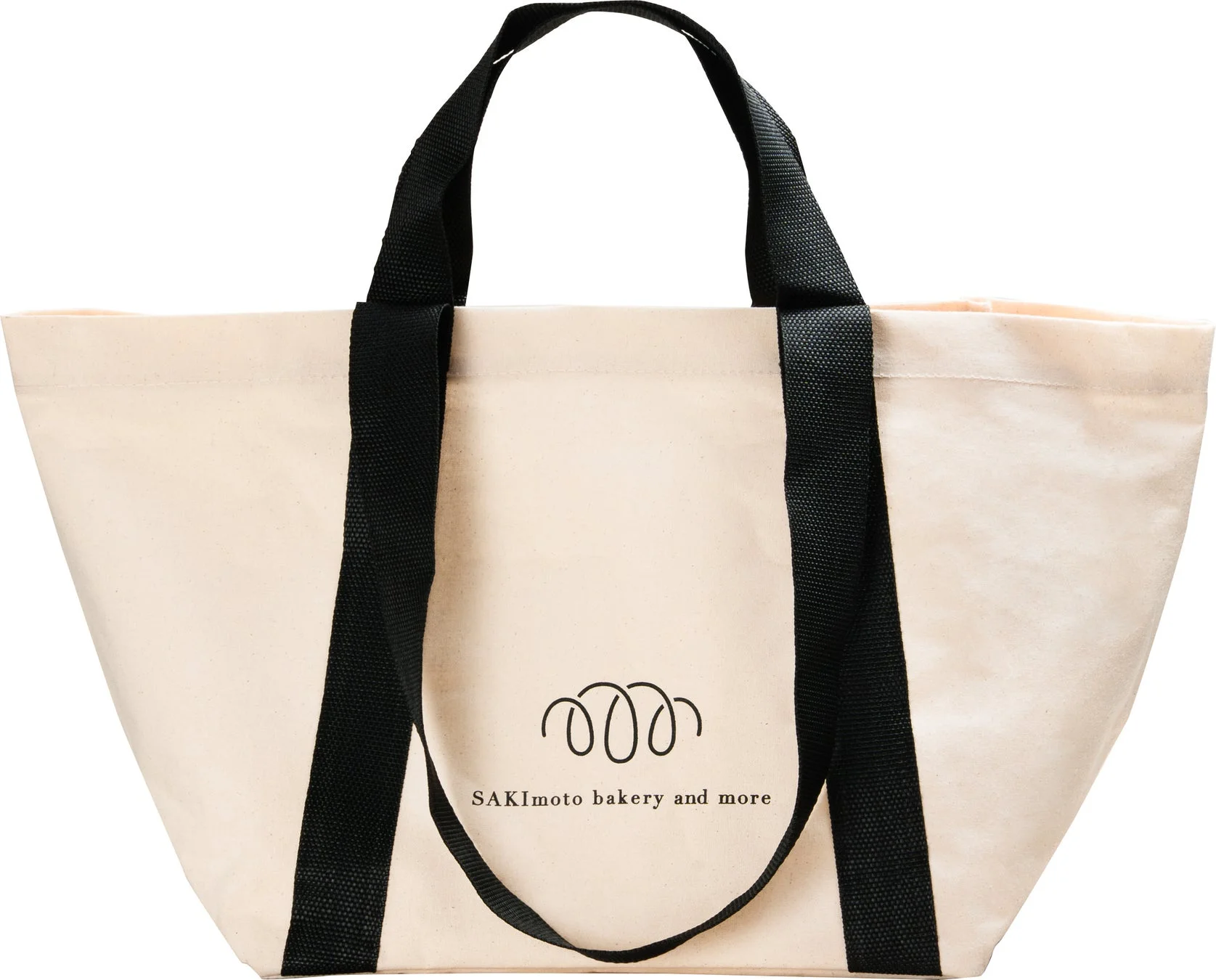 「SAKImoto bakery and more」のロゴが入った、ベージュ色のキャンバス製トートバッグが写っています。黒い持ち手が特徴です。