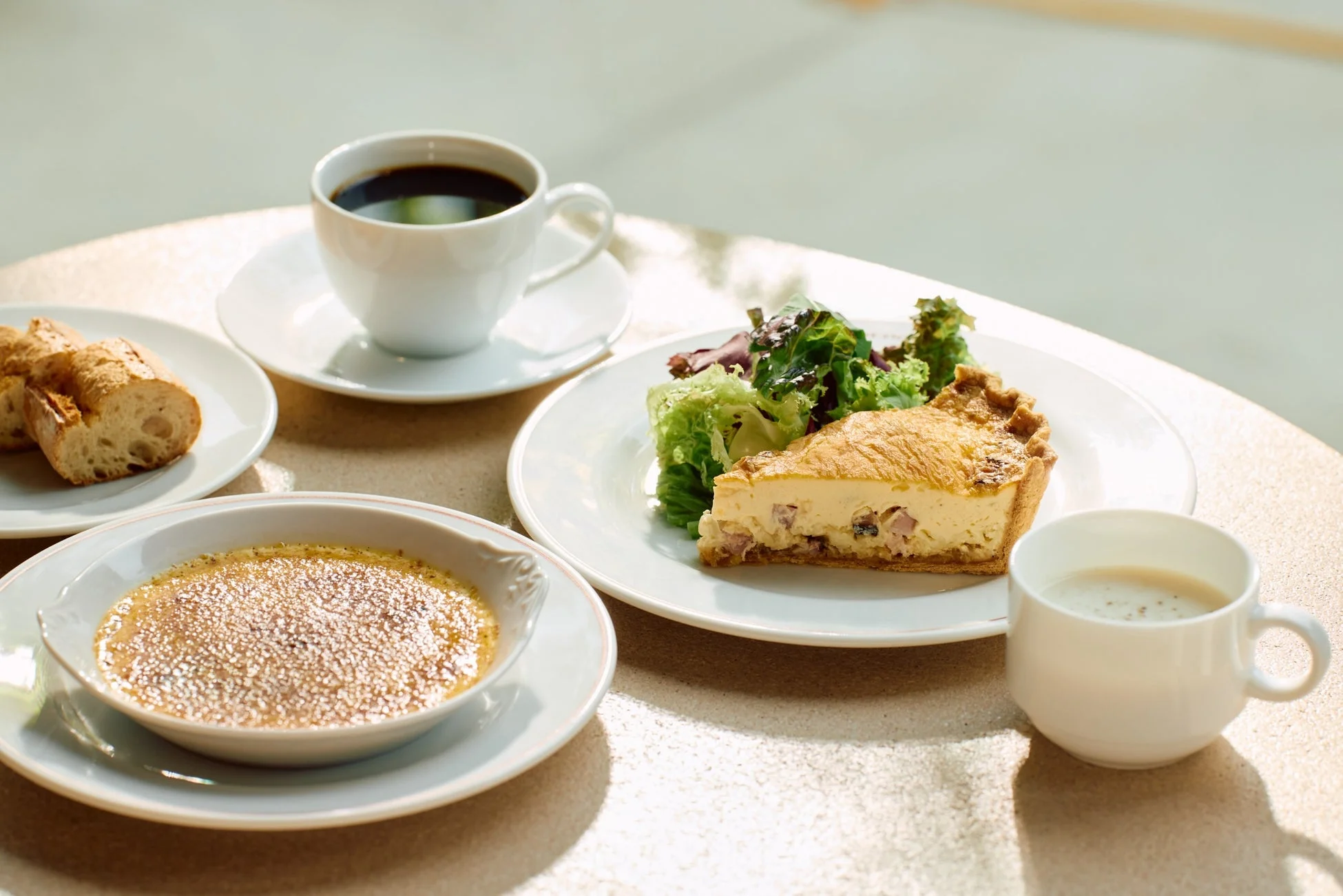 キッシュ、サラダ、パン、コーヒー、クレームブリュレの食卓