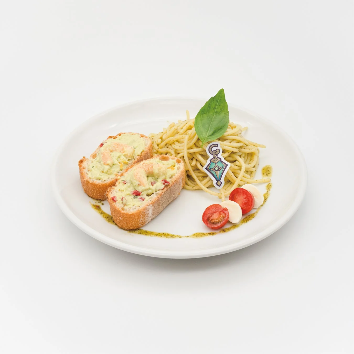 白い皿に盛り付けられた、ペストソースのパスタと、エビとクリームが乗ったパン2切れの料理。ミニトマト、モッツァレラチーズ、バジルの葉、キャラクターのピックが添えられている。