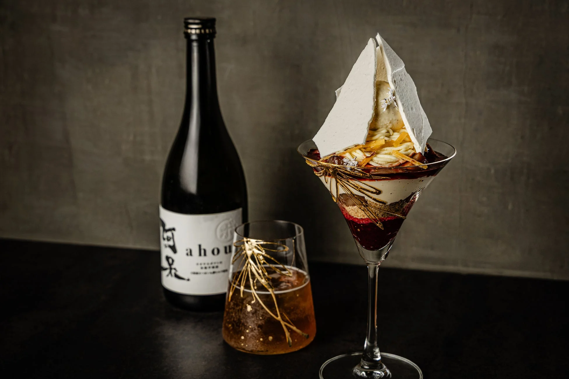 豪華な飾り付けのパフェと日本酒のボトル、グラスが並ぶ、高級感あふれる写真