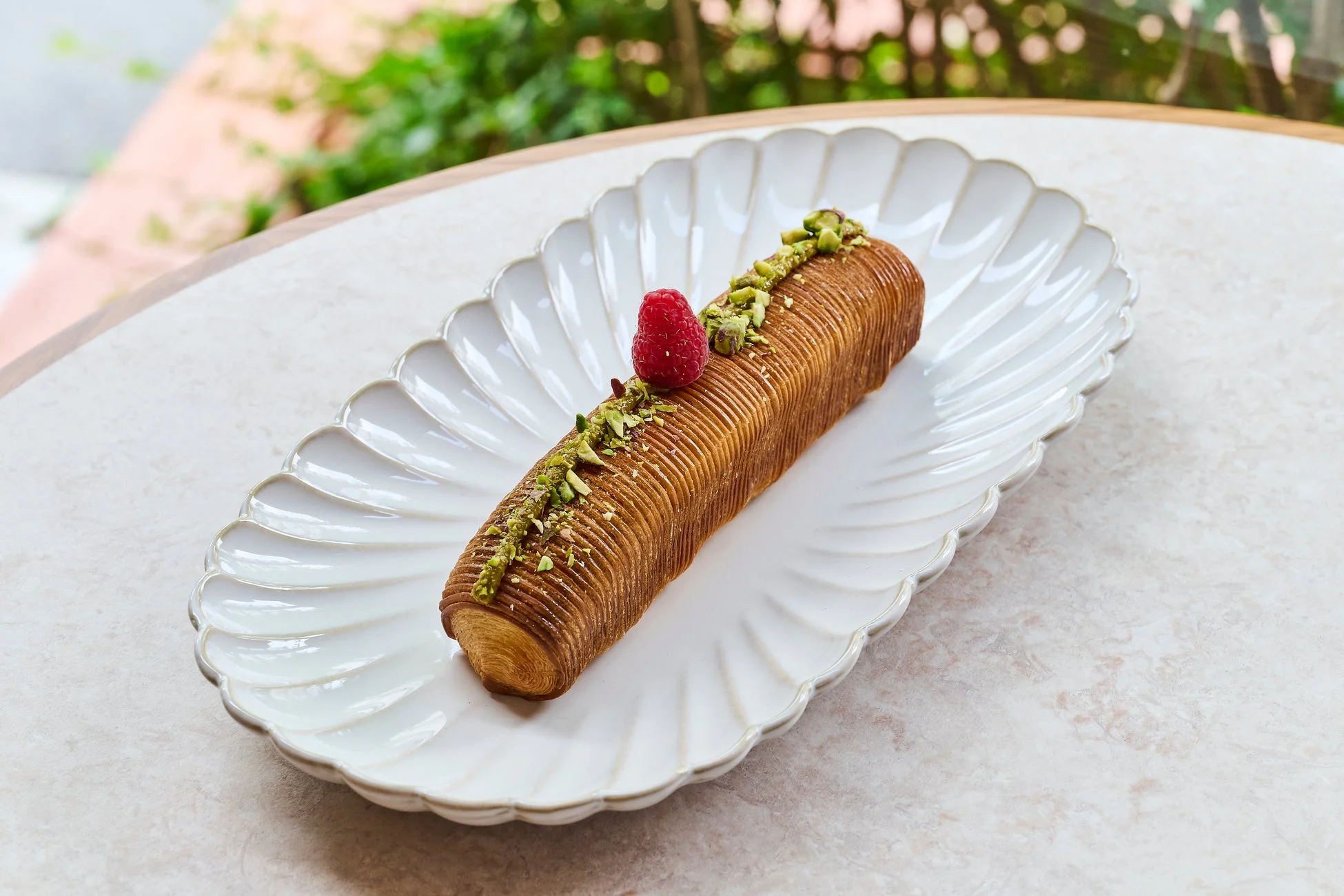 ラズベリーとピスタチオがトッピングされた黄金色のペストリー