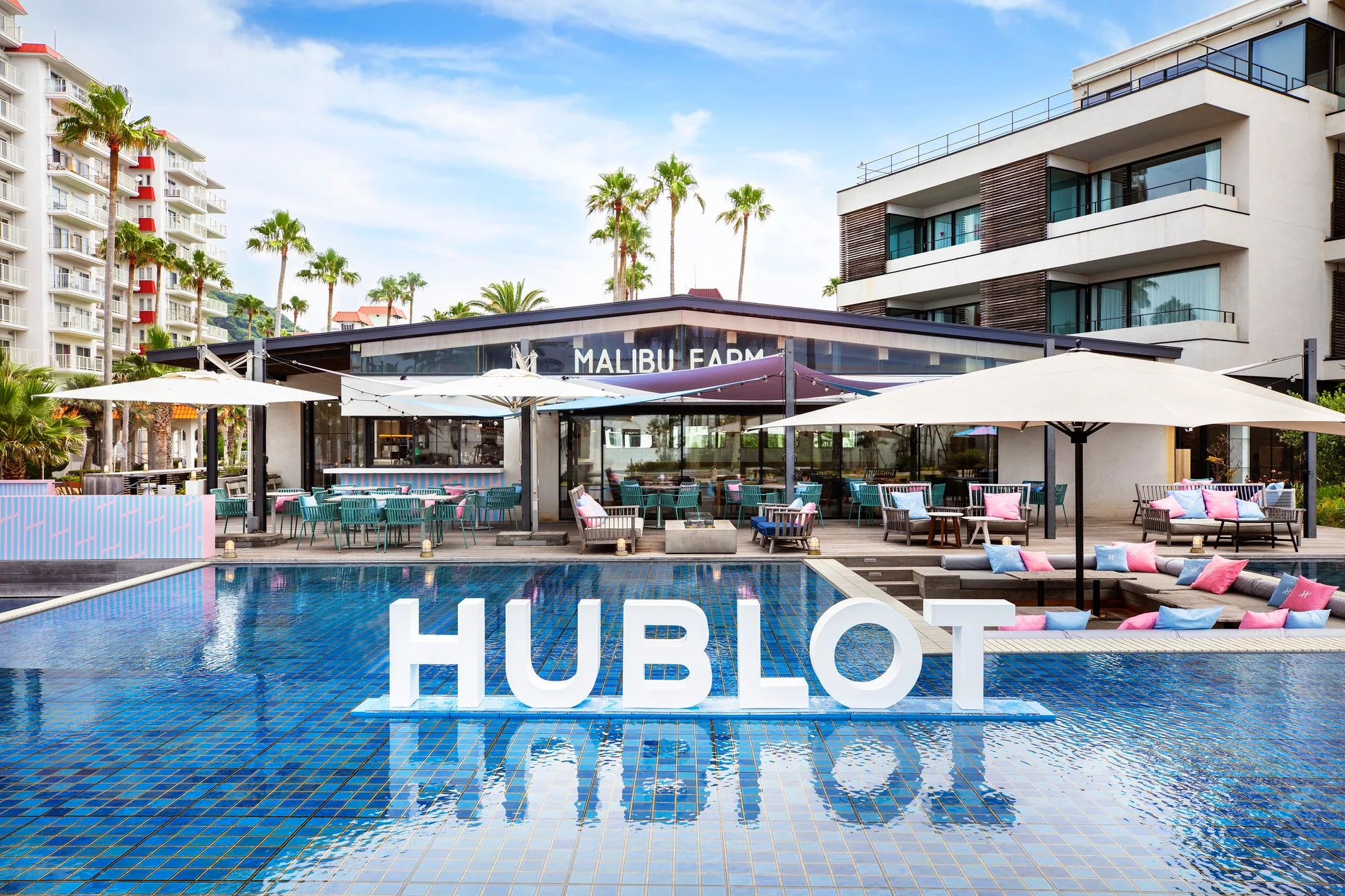 HUBLOTのロゴが浮かぶプールが印象的なリゾート地の風景