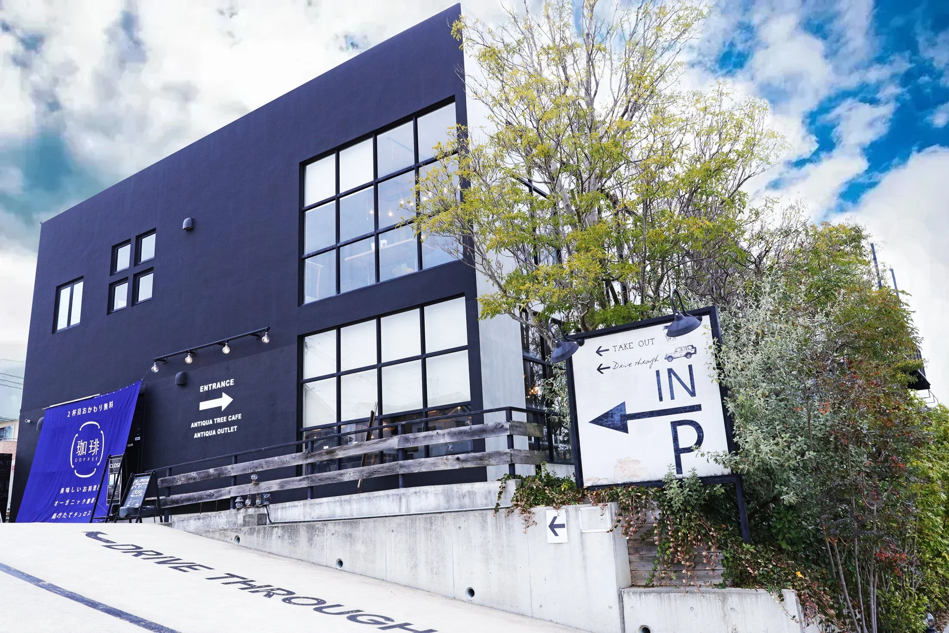 モダンな黒い外観の建物で、ANTIQUA TREE CAFEとANTIQUA OUTLETが入居しているようです。ドライブスルーとテイクアウトのサービスを提供しており、コーヒーや食事が楽しめる場所と推測されます。
