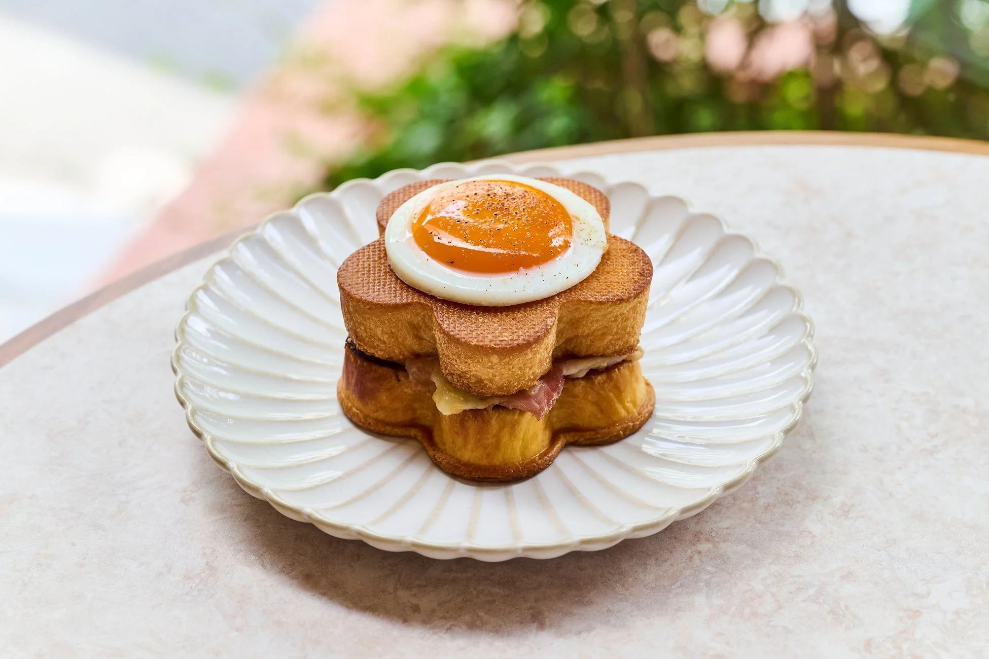 花の形をしたフレンチトーストに半熟の目玉焼きが乗っており、ハムとチーズが挟まれている