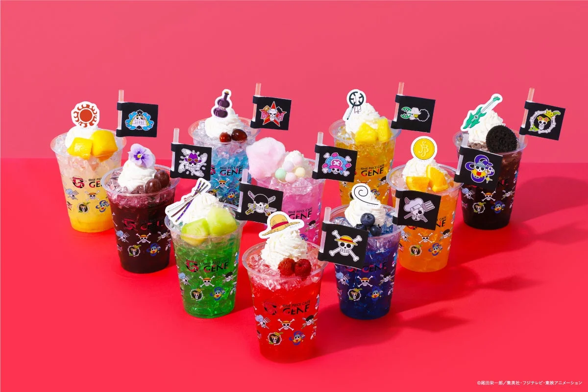 赤色の背景に、人気アニメ「ワンピース」のキャラクターをテーマにしたカラフルなドリンクが多数並べられています。各ドリンクはフルーツやホイップクリームで飾られ、キャラクターの旗やモチーフが添えられています。ONE PIECE CAFE GENEのコラボメニューと思われます。