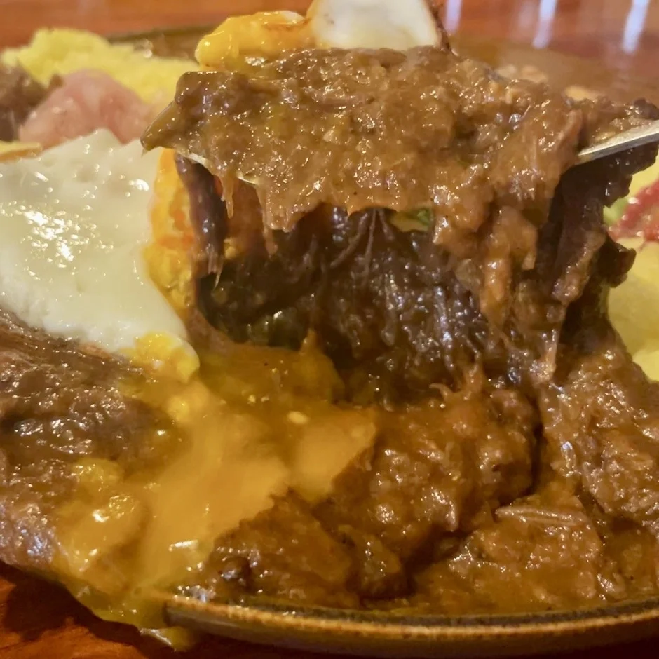 煮込まれた肉料理と半熟の目玉焼き