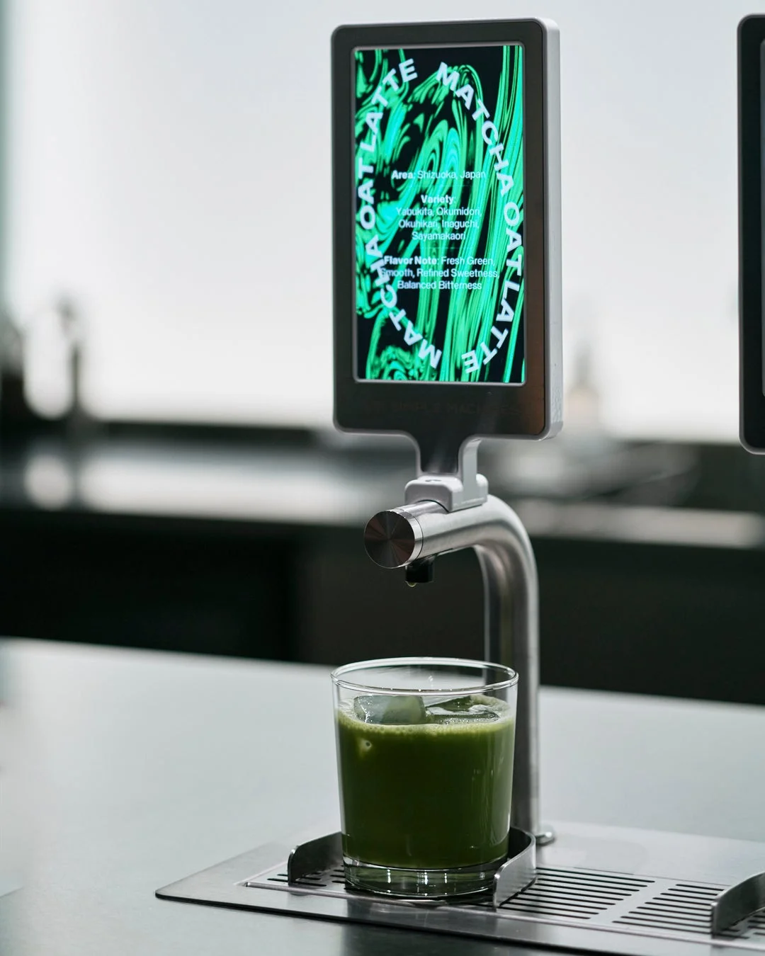 現代的なディスペンサーから抹茶オーツラテが注がれている様子