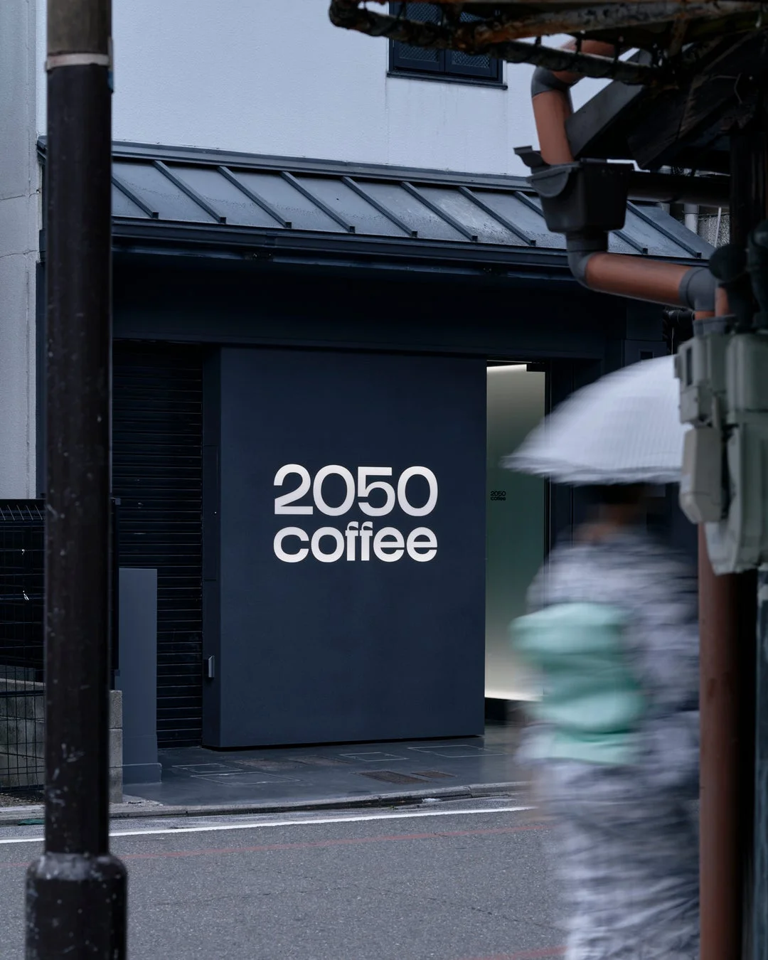 雨の日に傘をさした人物が通り過ぎる「2050 coffee」