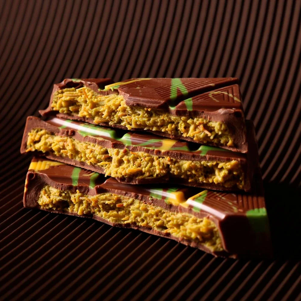 割れたチョコレートバーが積み重ねられ、ミルクチョコレートの中に黄色みがかった緑色のフィリングが詰まっている