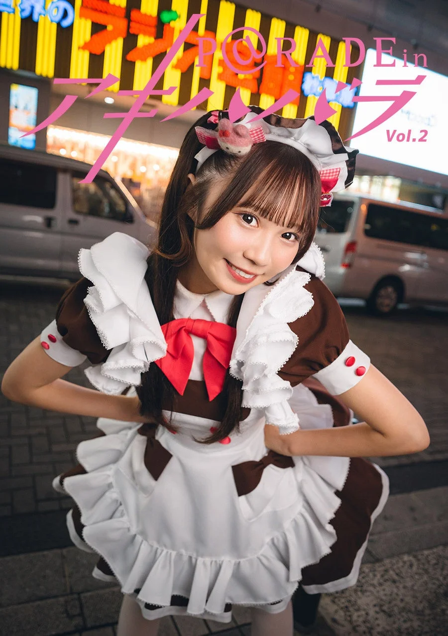 夜の街中でメイド服を着た若い女性が笑顔でポーズをとっています。