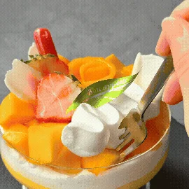 マンゴー、ホイップクリーム、イチゴがたっぷり盛り付けられた、鮮やかで美味しそうなパフェのクローズアップ