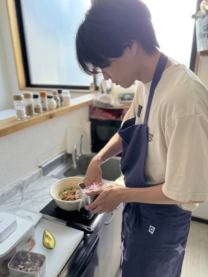 エプロンをつけた男性がキッチンで料理をする様子