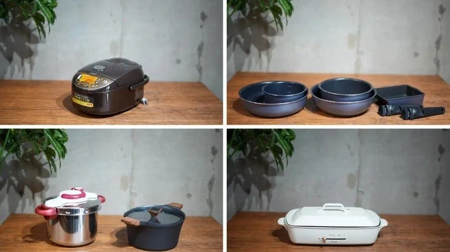 木製の台の上に、炊飯器、圧力鍋、鍋類、電気ホットプレートなど、様々なキッチン家電と調理器具