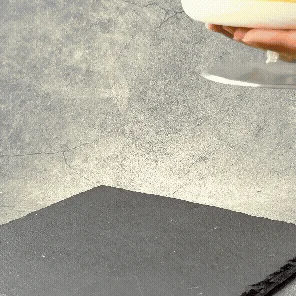 白い器に入ったなめらかなデザートを黒いプレートに置く様子