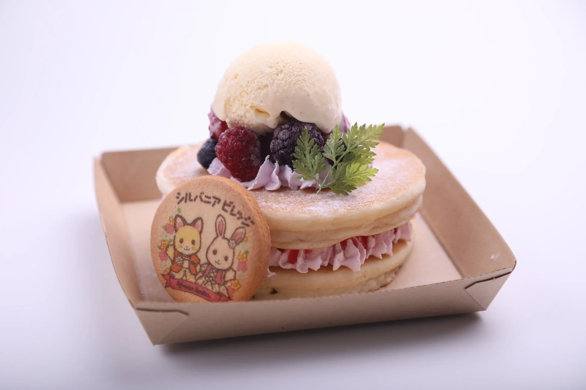 バニラアイスとミックスベリーが乗ったパンケーキが紙皿に盛られています。シルバニアファミリーのキャラクターが描かれたクッキーが添えられており、可愛らしいデザートです。